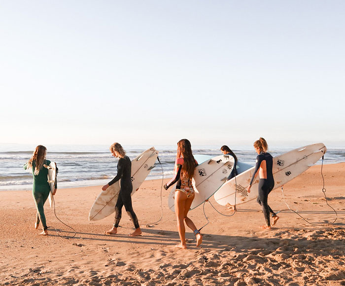 Grupo de mujeres por ingresar al mar con tablas de surf | Beneficios MP