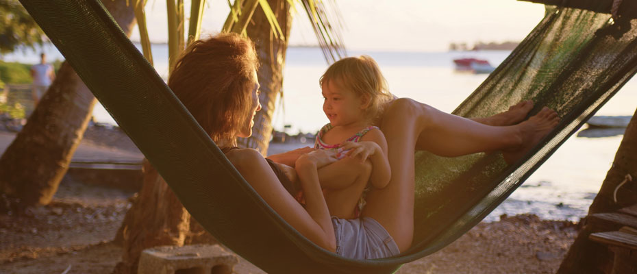 Mujer con una beba en una hamaca paraguaya en la playa | Pareja con una niña y un perro caminando en un bosque | Enriquecer las vacaciones creando momentos valiosos