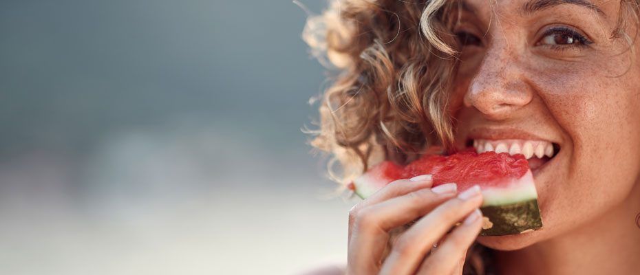 Mujer comiendo un trozo de sandía | El poder antiinflamatorio de las frutas de verano